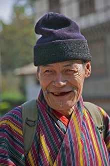 Smile Gallery: An old man at Trashigang wearing the traditional gho robe of all Bhutanese men