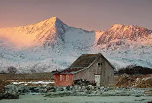 Sommeroy Prints: Old red wooden barn (rorbu) and snow-covered mountains at sunrise