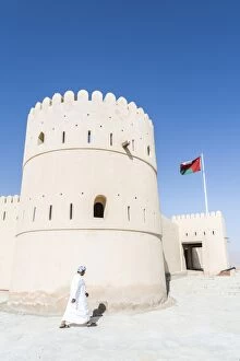 Images Dated 8th April 2014: Oman, Sur. Omani man walking to the entrance of Sunaysilah old fortress