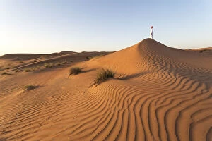 Images Dated 24th June 2014: Oman, Wahiba Sands. Man with omani dress on the sand dunes at sunrise (MR)