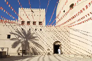 Horizontal Gallery: An Omani man walks into Bahla Fort decorated to celebrate the birthday of Sultan Qaboos