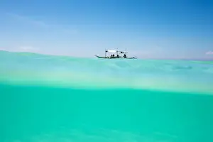 Horizon Prints: Over-under shot of Philippine outrigger boat in turquoise ocean water off the coast