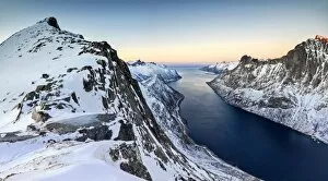 Panorama of snowy mountains and icy sea surrounding Peak Barden at sunset Ornfjorden