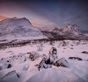 Panorama of snowy peaks surrounded by frozen sea under orange clouds at sunset Panorama of snowy peaks surrounded by frozen sea under orange clouds at sunset