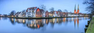 Panorama of typical houses and towers of cathedral reflected in river Trave at dusk