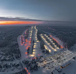 Ski Resort Prints: Panoramic aerial view of people skiing on the snowy ski slopes of Iso Syote winter resort at dusk