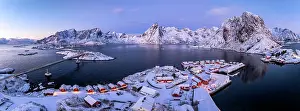 Rooftop Prints: Panoramic aerial view of snowy rorbu cabins overlooking the cold sea at winter dusk