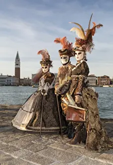 Three people in costume at Carnival time, San Giorgio Maggiore, Venice, Veneto, Italy
