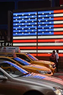 Times Square Prints: People walking past Neon sign of American Flag on Times Square, New York, Manhattan, USA