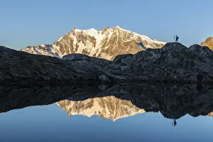Images Dated 24th November 2020: Photographer on rocks admiring Monte Rosa mirrored in water from Monte Moro Pass
