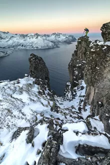 Photographer on the rocks on top of Mount Hesten admires the Mefjorden and the frozen
