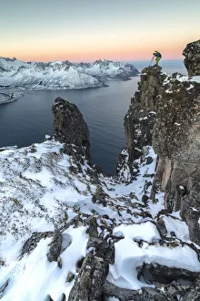 Photographer on the rocks on top of Mount Hesten admires the Mefjorden and the frozen Photographer on the rocks on top of Mount Hesten admires the Mefjorden and the frozen