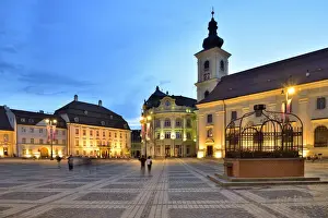 Religious Site Prints: Piata Mare and the Holy Trinity Roman Catholic Church at dusk. Sibiu, Transylvania