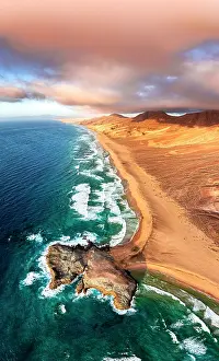Wave Prints: Pink clouds at sunset over the golden sand of Cofete beach and headland