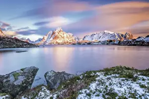 Reine Prints: The pink sky at sunrise illuminates Reine village with its cold sea and the snowy peaks
