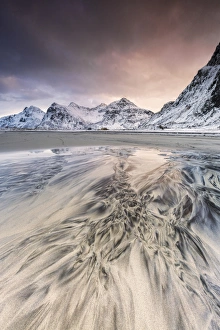Pink sky on the surreal Skagsanden beach surrounded by snow covered mountains Pink sky on the surreal Skagsanden beach surrounded by snow covered mountains