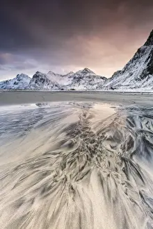 Pink sky on the surreal Skagsanden beach surrounded by snow covered mountains