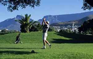 Golf Prints: A player tees off at the golf course at Green Point overlooked by Table Mountain