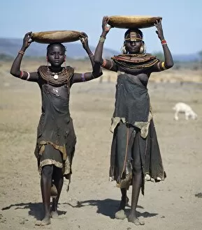 Pokot Collection: Two Pokot girls carry water in wooden containers on their heads