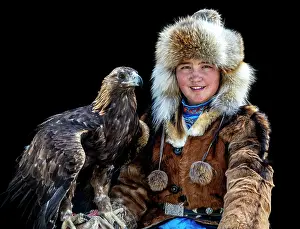 Mongolia Prints: Portrait of a young female Kazakh Eagle Hunter posing with her trained golden eagle