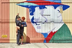Images Dated 11th March 2022: Professional Tango Dancers in front of a wall art of the historical tango artist Carlos Gardel in