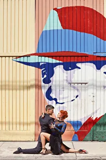 Images Dated 11th March 2022: Professional Tango Dancers in front of a wall art of the historical tango artist Carlos Gardel in