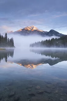 Pyramid Mountain in the Canadian Rockies surrounded by mist and reflected in Pyramid Lake