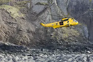 RAF helicopter performing a coastal rescue at the base of the steep cliffs of Spekes