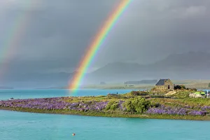A rainbow over the church of the Good Shepherd and the lupins in bloom by the lake on a
