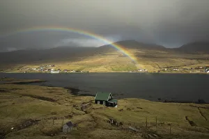 Cloudy Sky Prints: A rainbow above a solitary house in Nesvik. Streymoy, Faroe Islands