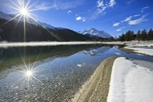 Rays of winter sun illuminate Lake Silvaplana still partially frozen Maloja Engadine