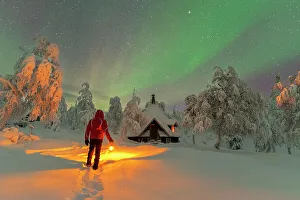 Bright Gallery: Rear a man with lantern admiring northern lights (aurora borealis) from a finnish hut (kota)