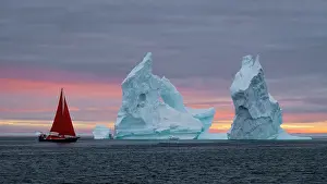 Danish Territory Prints: Red sailboat at sunset near icebergs in Disko Bay, Greenland