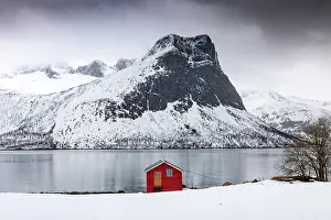 Timber Prints: Red timber rorbu (cabin) with Bergsfjord and snow-covered mountains in the distance