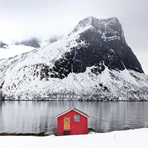 Timber Prints: Red timber rorbu (cabin) with Bergsfjord and snow-covered mountains in the distance