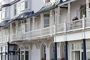 Images Dated 28th June 2011: Retired couple sat on balcony, Regency houses, Sidmouth, Devon, UK