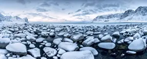Unstad Prints: Rocks in the cold sea and snow capped mountains under the blue light of dusk Unstad