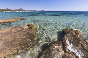 Rocks frame the turquoise water of sea around the sandy beach of Sant Elmo Castiadas