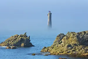 Sea Smoke Prints: Rocky coast at Pointe de Pern with lighthouse of Nividic in fog - France, Brittany