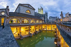 The Roman Baths and Bath Cathedral illuminated at dusk, Bath, Somerset, England