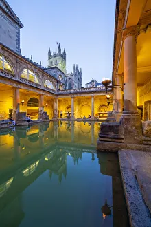 The Roman Baths and Bath Cathedral illuminated at dusk, Bath, Somerset, England