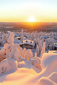 Rooftop Prints: Romantic sunrise over ice sculptures surrounding traditional mountain huts covered with snow