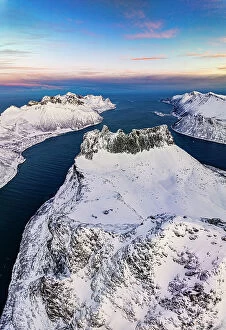 Fjord Collection: Romantic sunrise over the snowy peak of Grytetippen mountain along the icy sea, aerial view