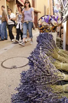 Shoppers Prints: Rousillion; France. People walking down a street with lavender for sale in the foreground