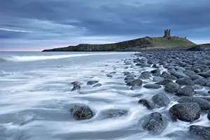 The ruins of Dunstanburgh Castle overlooking the boulder strewn shores of Embleton Bay