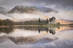 Images Dated 5th May 2020: The ruins of Kilchurn Castle reflected in Loch Awe at dawn on a misty morning in the