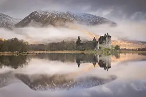 The ruins of Kilchurn Castle reflected in Loch Awe at dawn on a misty morning in