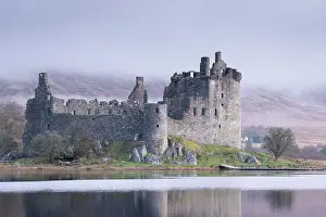 The ruins of Kilchurn Castle reflected in Loch Awe at dawn on a misty morning in the Scottish Highlands, Argyll and Bute, Scotland. Winter (March) 2017