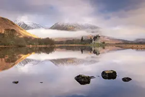 The ruins of Kilchurn Castle reflected in Loch Awe at dawn on a misty morning in the Scottish Highlands, Argyll and Bute, Scotland. Winter (March) 2017