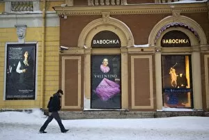 Advert Gallery: Russia, St. Petersburg; A man walking in front of high end clothes adverts in the city centre in